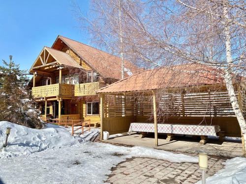 een groot houten huis met een paviljoen in de sneeuw bij Сакский Двор in Besqaynar