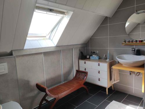 W łazience znajduje się umywalka i drewniane krzesło. w obiekcie Chambre proche paris JO 2024 w mieście Chaumontel