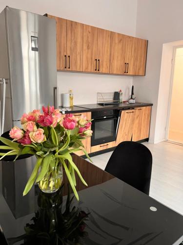 a kitchen with a table with a vase of pink flowers at Apartament 2 pokoje, Przemyśl, 1 piętro in Przemyśl