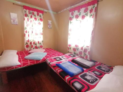 a small room with two beds in it with curtains at BATAD CRISTINA'S Main Village INN & Restaurant in Banaue