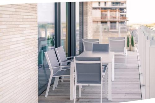 a white table and chairs on a balcony at Huswell - Modern new apartment with pool access and parking in Ostend