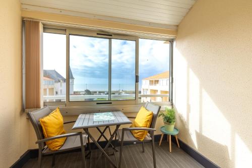 un balcon avec une table, des chaises et une fenêtre dans l'établissement La Corniche d'Or - Appt à 150m de la plage, à Saint-Hilaire-de-Riez