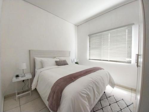 a white bedroom with a large bed and a window at 931 Ballito Groves in Ballito