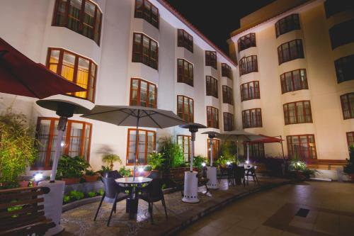 a hotel with tables and umbrellas in a courtyard at Xima Exclusive Cusco in Cusco