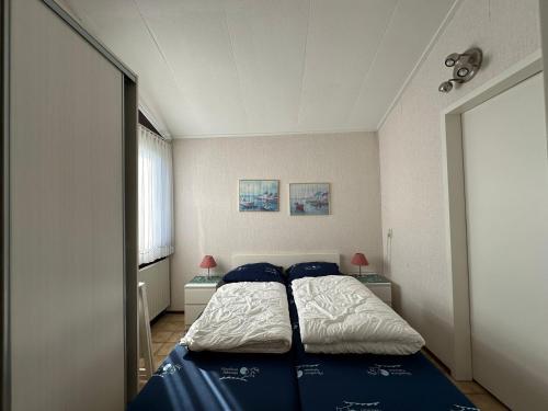 1 dormitorio con 1 cama con sábanas azules y almohadas azules en Heggerank 19A*, en Nieuwvliet