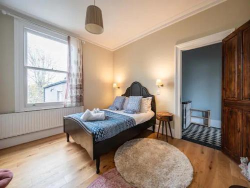 1 dormitorio con cama, ventana y alfombra en Pass the Keys Stylish London Flat near Station - Victoria 20 min, en Londres