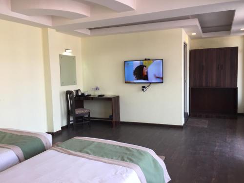 a room with two beds and a tv on the wall at Hotel Serenity in Kathmandu