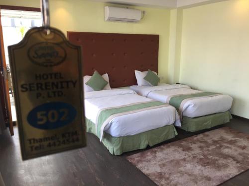 two beds in a hotel room with a sign next to them at Hotel Serenity in Kathmandu