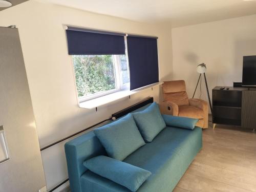a living room with a blue couch and a window at Apartman Maksimir Rebro Jordanovac Luka in Zagreb