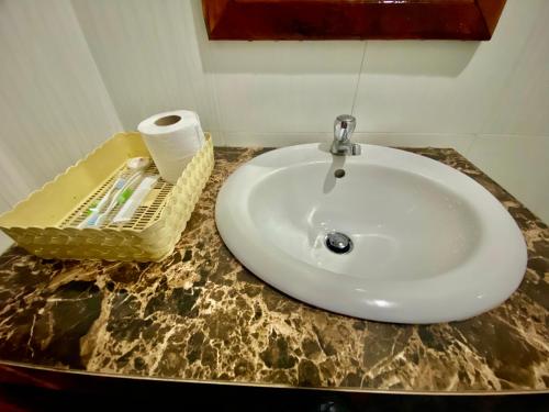 a bathroom sink with a roll of toilet paper on a counter at Golden Papaya Guesthouse in Siem Reap