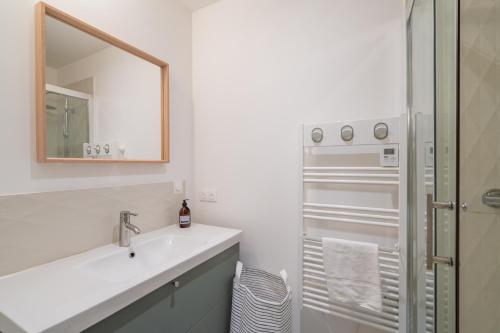 une salle de bain blanche avec un lavabo et un miroir dans l'établissement Les 3 Cigales - Bel appartement proche vieux port, à Marseille