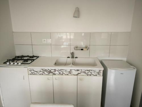 a white kitchen with a sink and a stove at Studio Sylvain in Neuilly-lʼÉvêque