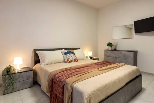 una camera con un grande letto e una TV a schermo piatto di White lilium apartment - Magnolia holidays ad Alghero