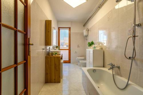 e bagno con vasca, servizi igienici e lavandino. di White lilium apartment - Magnolia holidays ad Alghero