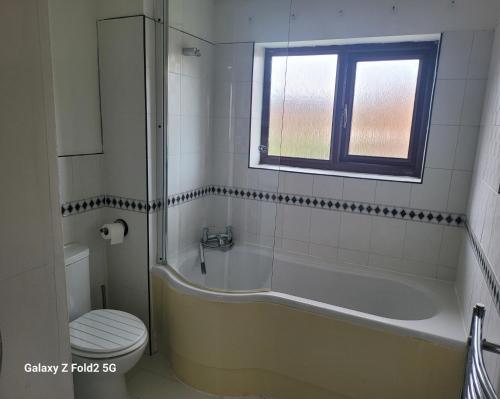 a bathroom with a tub and a toilet and a window at Homely place in Theale
