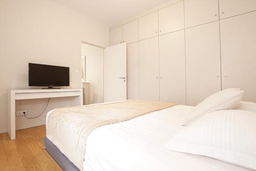 - une chambre blanche avec un lit et une télévision dans l'établissement Appartement T2 de Luxe face au Jardin Public, à Bordeaux