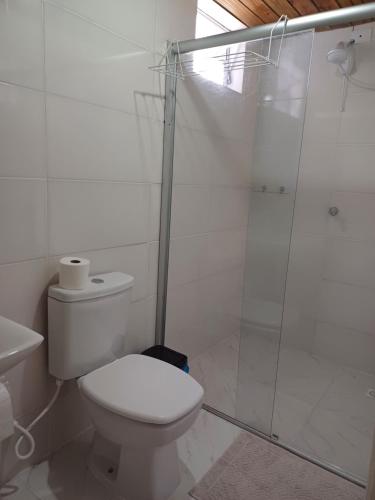 a bathroom with a toilet and a glass shower at Suíte Pachamama in Bombinhas