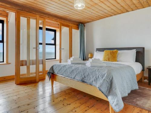 a bedroom with a large bed with wooden floors and windows at Pass the Keys Beautiful Sea View House in Borth