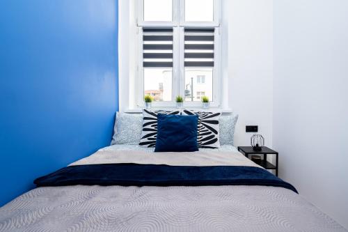 a blue bedroom with a bed and a window at Apartament Indygo16 in Kalisz