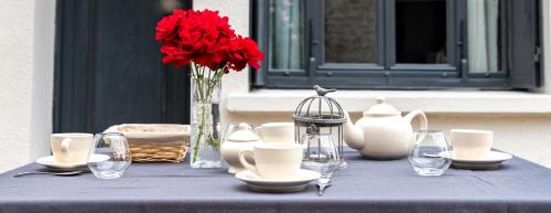a blue table with a vase of red flowers and glasses at La p'tite maison in Blacy