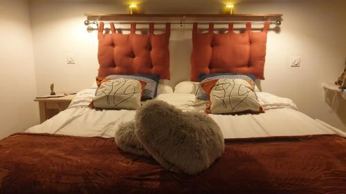 - une chambre avec un lit doté d'une tête de lit orange et d'oreillers dans l'établissement Love Room- Spa- Escale Amoureuse, à Puygaillard-de-Quercy