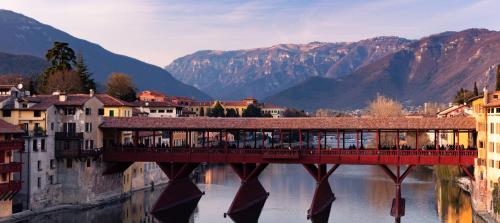 a bridge over a river with buildings and mountains at Green House in Bassano del Grappa