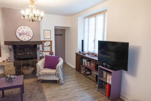 a living room with a flat screen tv and a chair at La p'tite maison in Blacy