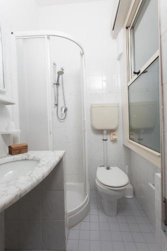 a white bathroom with a toilet and a shower at Hotel Atlantic in Gatteo a Mare