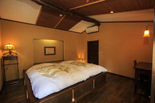 una camera da letto con un grande letto con lenzuola bianche di Kinokuniya Ryokan a Hakone