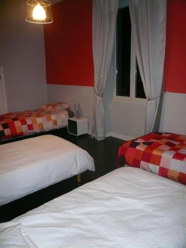 two beds in a room with red and white at Gîte le chant des tournesols piscine chauffée in Montirat
