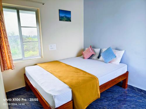 małe łóżko w pokoju z oknem w obiekcie RPM home stay w mieście Tiruvannamalai