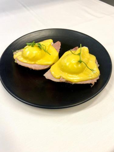 a black plate with two sandwiches with yellow sauce at Hintlesham Hall Hotel in Ipswich