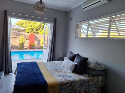 a bedroom with a bed and a window and a pool at 1 CAMDEBO in Oudtshoorn