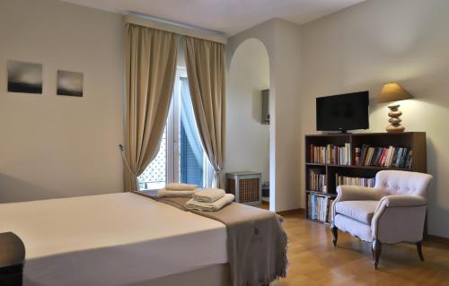 a bedroom with a bed and a chair and a television at Olive House Traditional Villa with Pool in Sitia