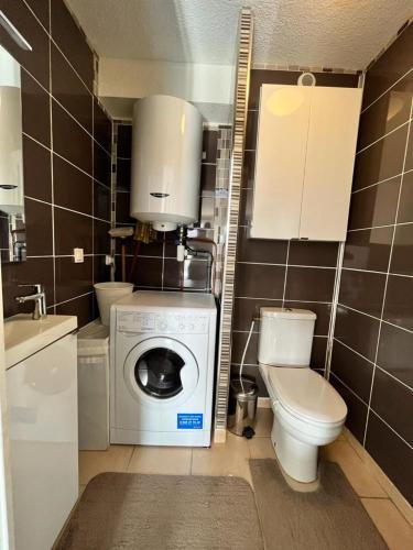 une salle de bain avec machine à laver et toilettes dans l'établissement Hag, à Valras-Plage