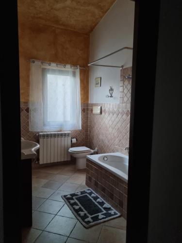 a bathroom with a tub and a toilet and a sink at Casa Oliena in Oliena