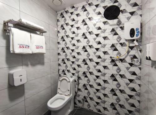 a bathroom with a toilet and a tile wall at Private Room with ensuite bathroom in Bukit Bakri in Bakri