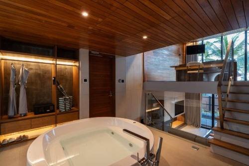 a large bathroom with a tub and a staircase at Casa De La Flora - SHA Extra Plus in Khao Lak
