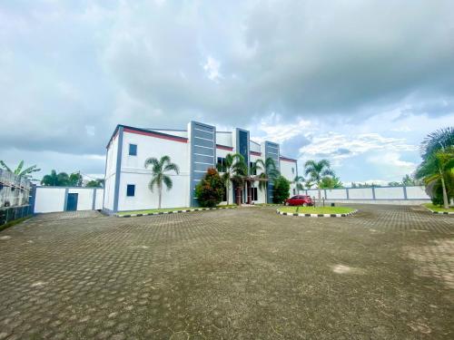 a white building with palm trees in front of the water at RedDoorz @ Wisma Graha Andi Djemma in Manda