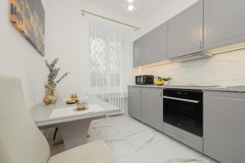 a kitchen with white cabinets and a white table at Royal Castle View Warsaw by Renters in Warszawa