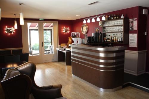 a bar in a restaurant with red walls at Contact Hôtel du Relais Thouars in Thouars