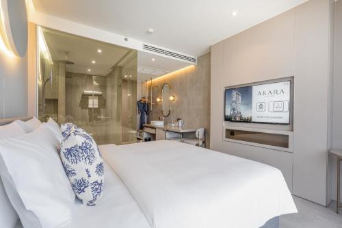 a bedroom with a large white bed and a television at Akara Hotel Pattaya in Pattaya North