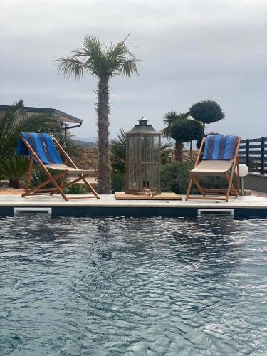 two chairs and a lantern next to a swimming pool at Villa Belissima Vista Mare in Selce