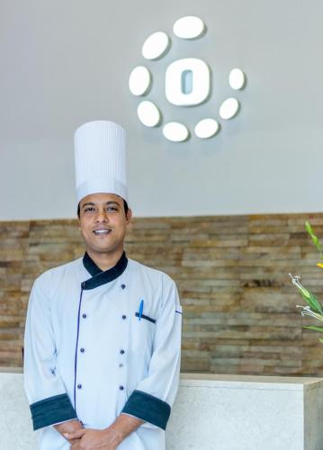 a man in a chefs hat standing in a kitchen at Octave Hotel & Spa - Sarjapur Road in Bengaluru