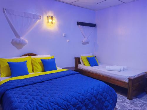 a bedroom with two beds with blue and yellow pillows at City Paradise Dambulla in Dambulla
