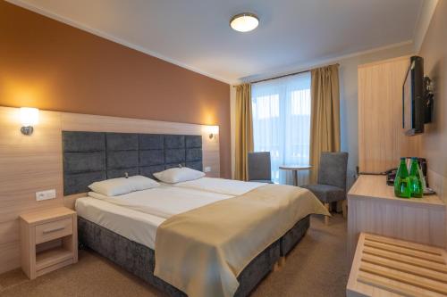a hotel room with a large bed and a chair at Pensjonat Carmen in Szklarska Poręba