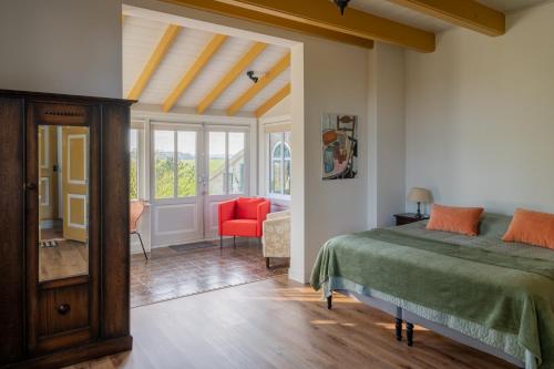 een slaapkamer met een bed en een rode stoel bij Kleinhoef - charmante, luxe kamers in een boerderij uit 1875 in Nigtevecht