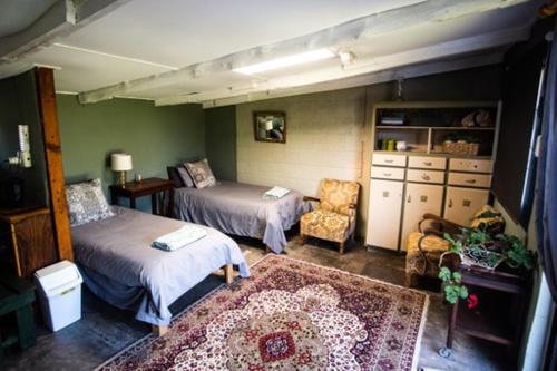 a bedroom with two beds and a chair and a rug at Clifford Selfcatering Guesthouse in Barkly East