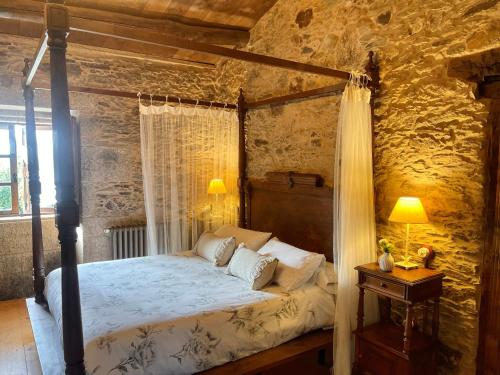a bedroom with a canopy bed in a stone wall at Casa de 3 habitaciones in Coirós