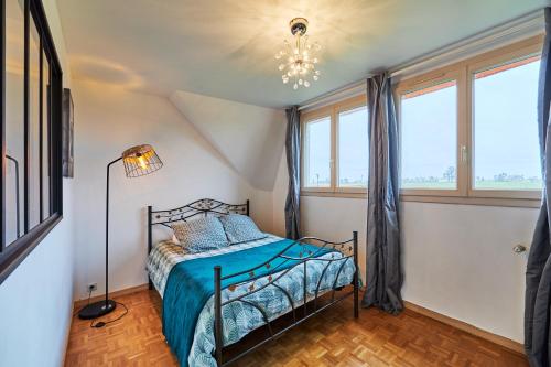 1 dormitorio con 1 cama en una habitación con ventanas en Maison Boisée - Charmante maison au calme 